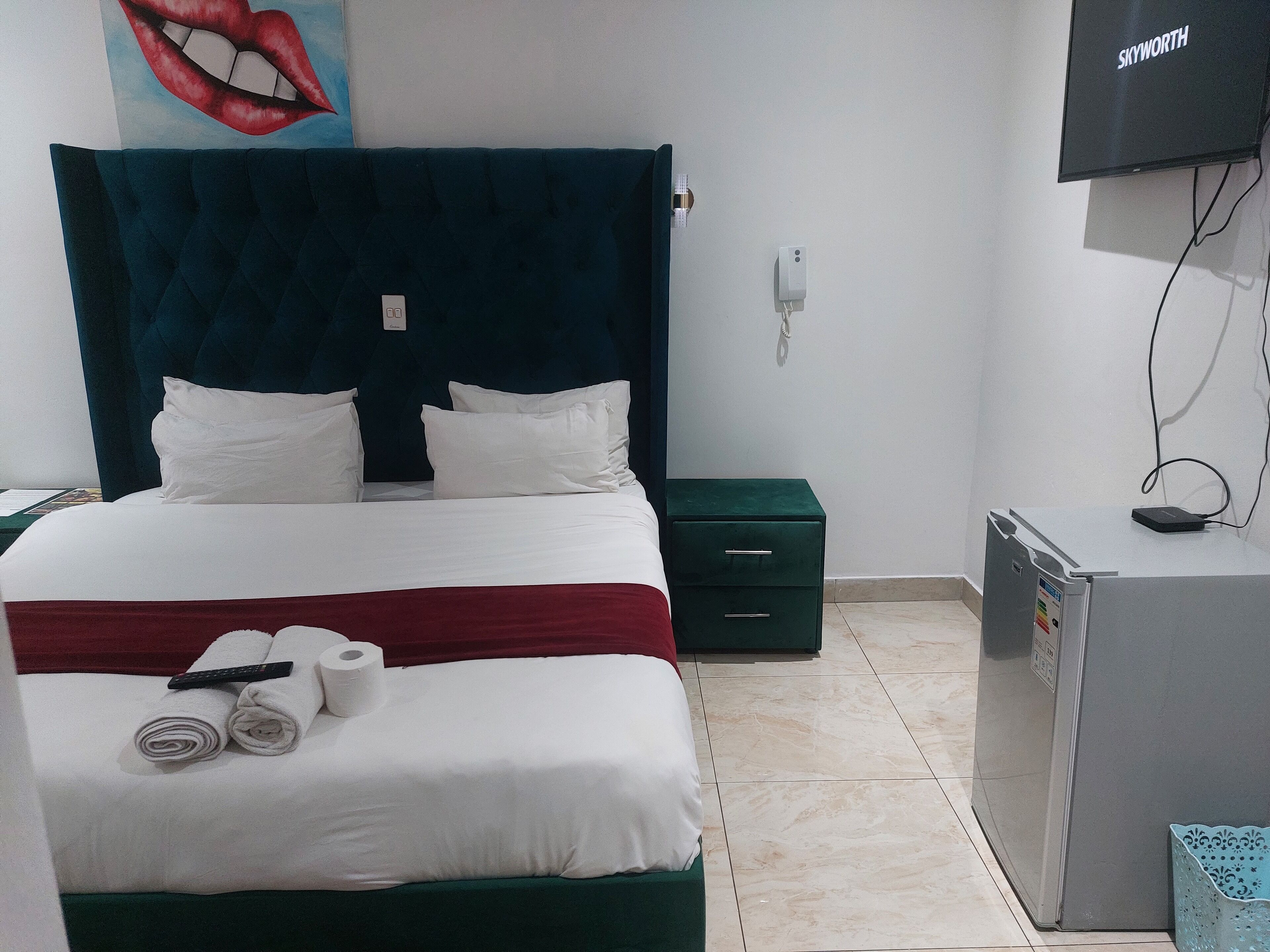 A hotel room with a bed, a desk, a TV, and a refrigerator.