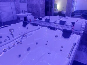 A modern bathroom with two large tubs, a sink, and a mirror. - Gold Crown international Hotel (Johannesburg South)