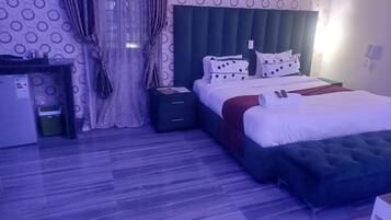 Una camera d'albergo con un letto, una scrivania, un cestino e un telefono fissato al muro.