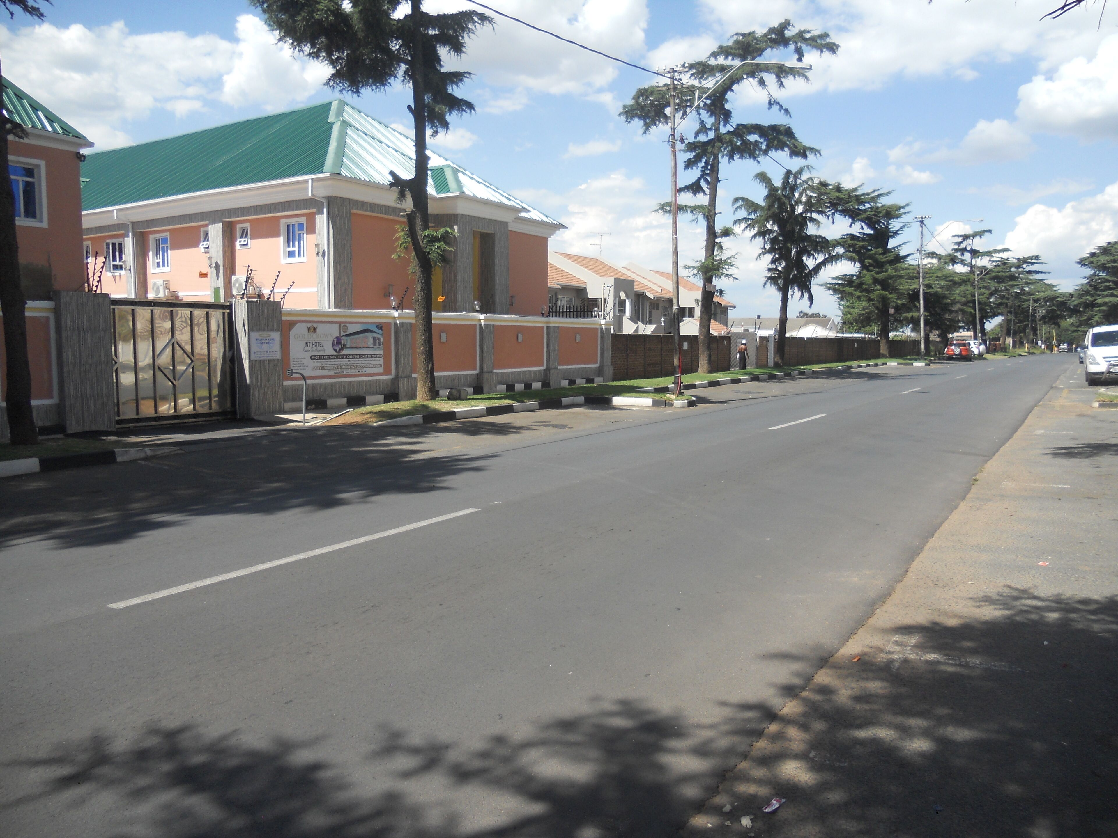 Vista de la calle con un hotel a la izquierda, que cuenta con una entrada protegida por una reja y un cartel.