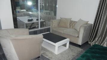 A modern living room with a beige sofa, a green velvet armchair, and a white coffee table.