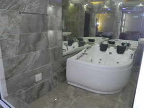 A modern bathroom with a large bathtub, a glass shower enclosure, and a marble-tiled wall. - Gold Crown international Hotel (Johannesburg South)