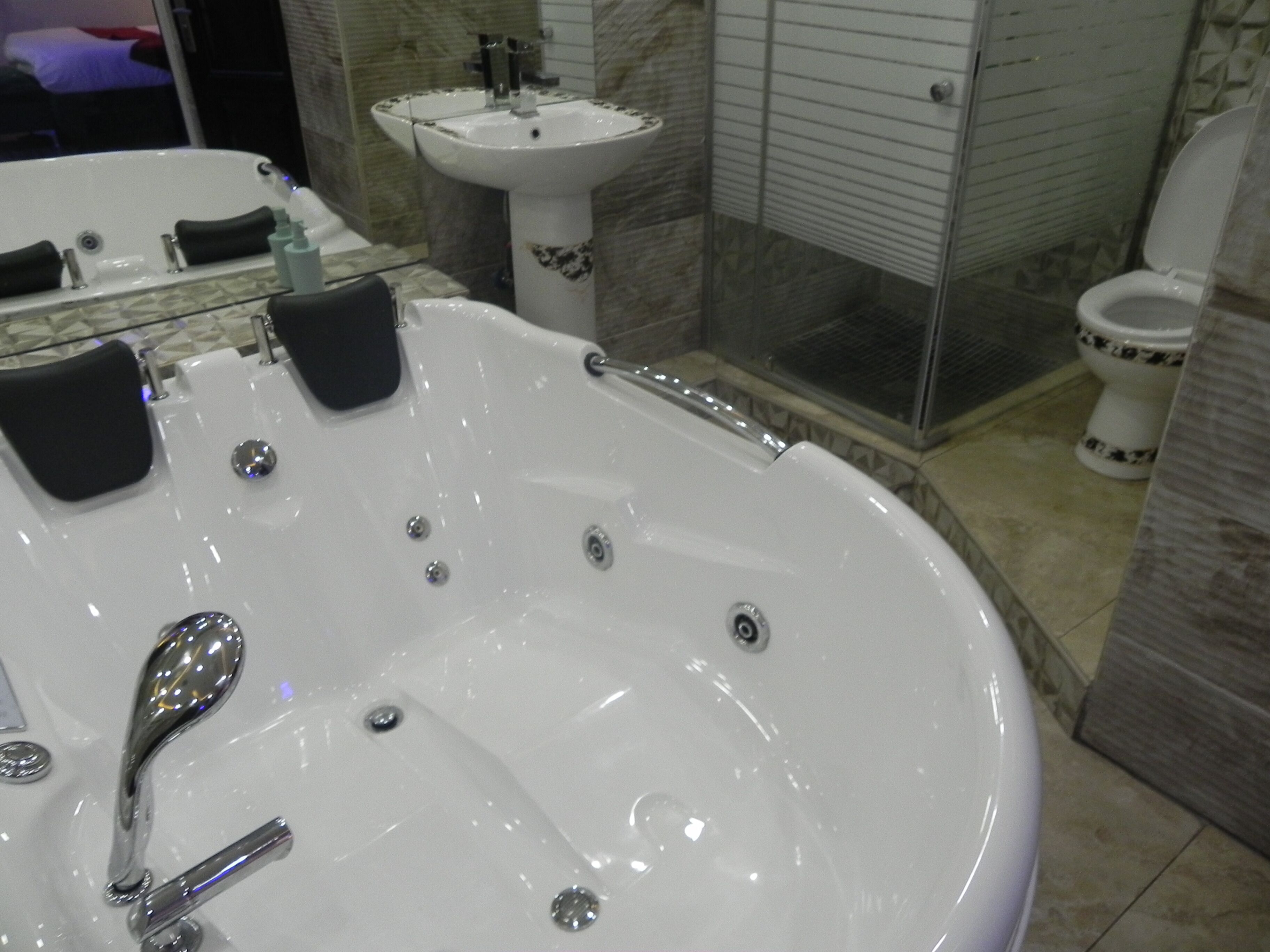 Une salle de bain avec une grande baignoire blanche, un lavabo et des toilettes.