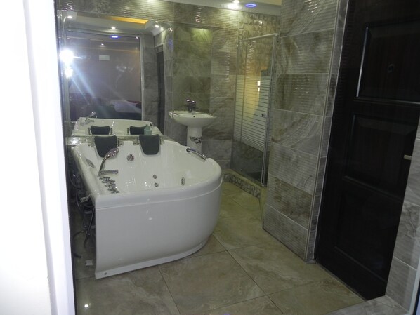Une salle de bain moderne avec une grande baignoire, un lavabo et un espace douche.