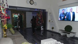 A lobby with a modern design, featuring a sofa, a decorative white console, and a television screen. - Gold Crown international Hotel (Johannesburg South)