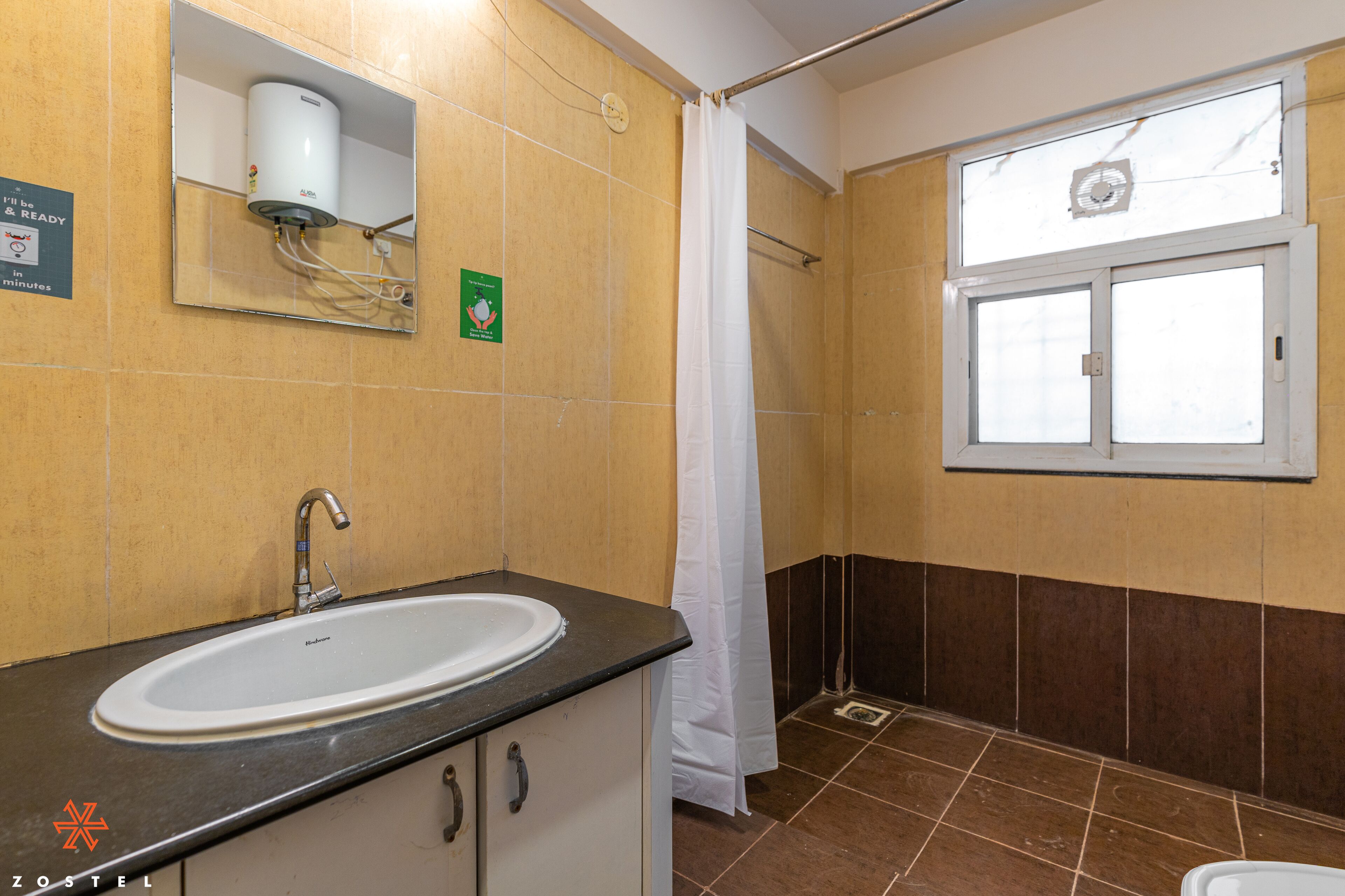 Une salle de bain avec un lavabo, un miroir, une douche et une fenêtre.