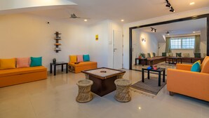 A modern living room with a sofa, coffee table, and a seating area with a bench. - Zostel Bangalore (Koramangala) (Bengaluru)