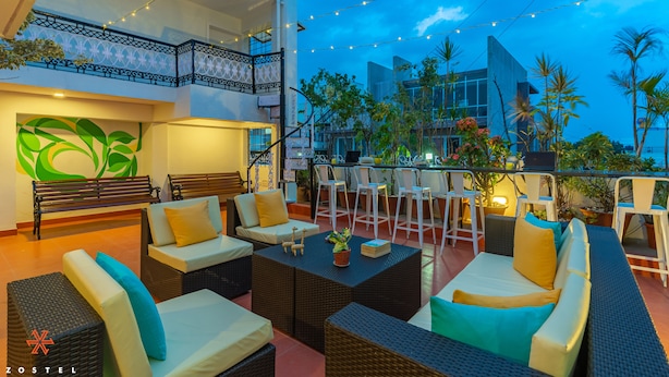 An outdoor seating area with wicker furniture and a balcony with string lights. - Zostel Bangalore (Koramangala) (Bengaluru)