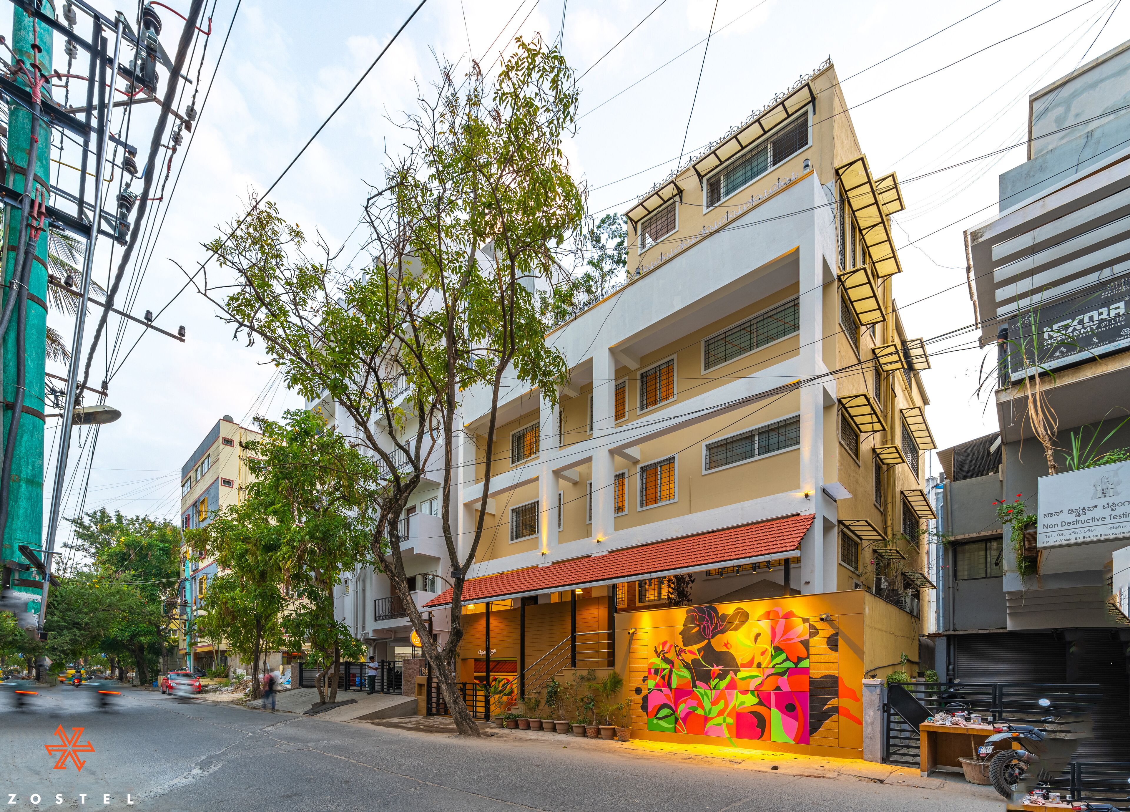 Un immeuble à plusieurs étages, doté d’un toit recouvert de tuiles rouges, d’une fresque colorée sur la façade et d’un escalier menant aux étages supérieurs.