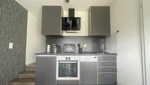 A compact kitchen with grey cabinets, a built-in oven, and a dishwasher. - Gryt Home Appartment L Nähe Nordsee (Ramhusen)