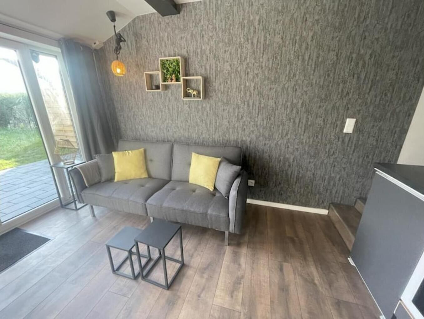 A modern living room with a grey sofa, two yellow cushions, a glass coffee table, and a grey cabinet.