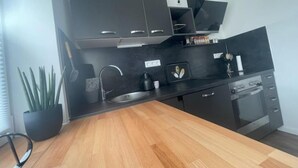 A modern kitchen with dark cabinets, a wooden countertop, a sink, and a dishwasher. - Gryt Home Fewo XXL Nähe Nordsee (Ramhusen)