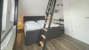 A compact bedroom with a bunk bed, wooden beams, and a ladder. - Gryt Home Fewo XXL Nähe Nordsee (Ramhusen)
