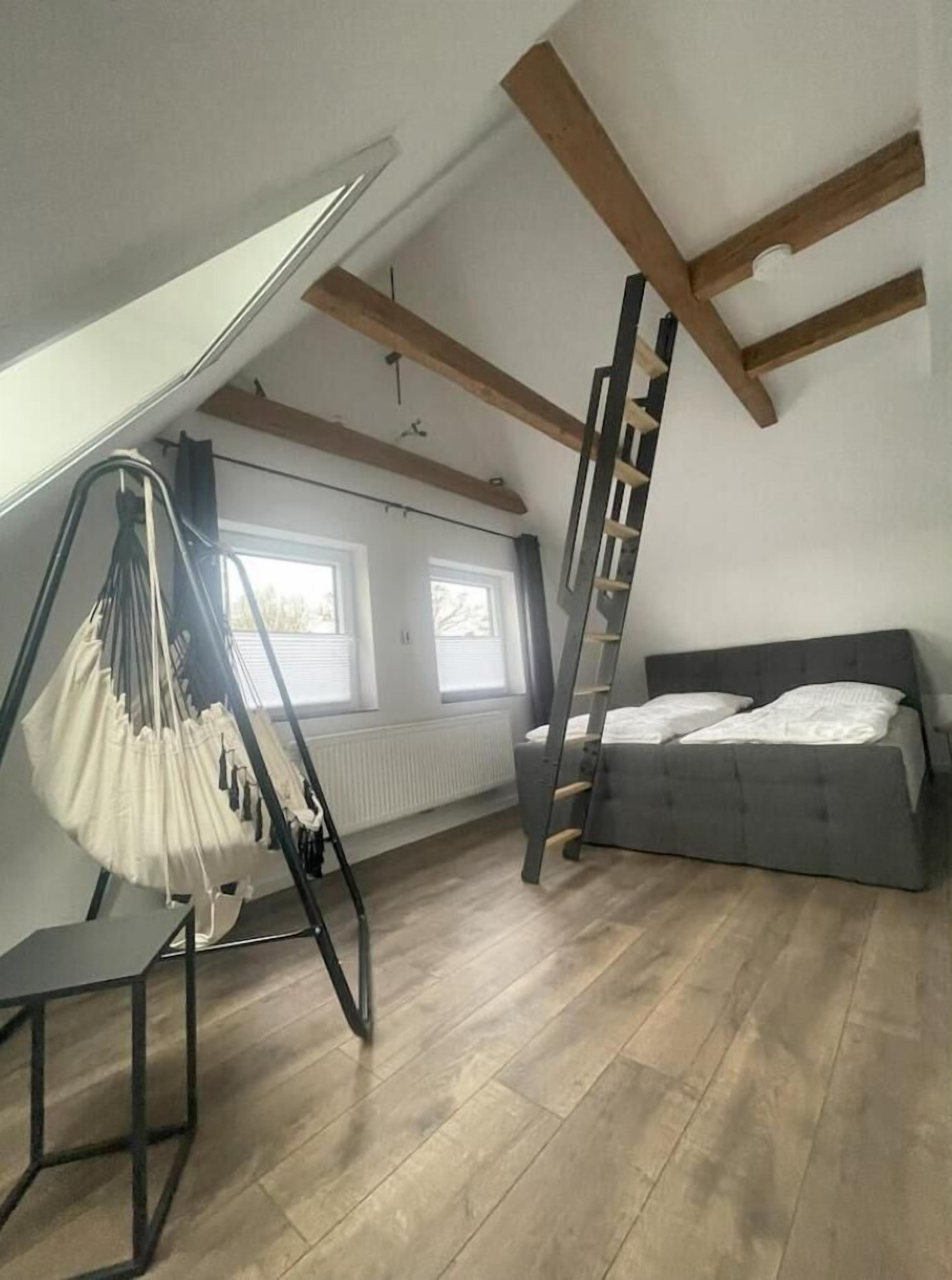 Ein Schlafzimmer im Loft-Stil mit einer Schlafkoje, einem Hängesessel und einer Leiter.