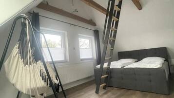 Ein Schlafzimmer im Loft-Stil mit einer Schlafkoje, einem Hängesessel und einer Leiter.