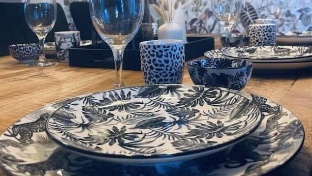 A dining table set with patterned plates, a clear glass, and a vase with dried flowers. - Gryt Home Fewo XXL Nähe Nordsee (Ramhusen)