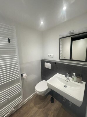 Un baño moderno con inodoro, lavabo y espejo.