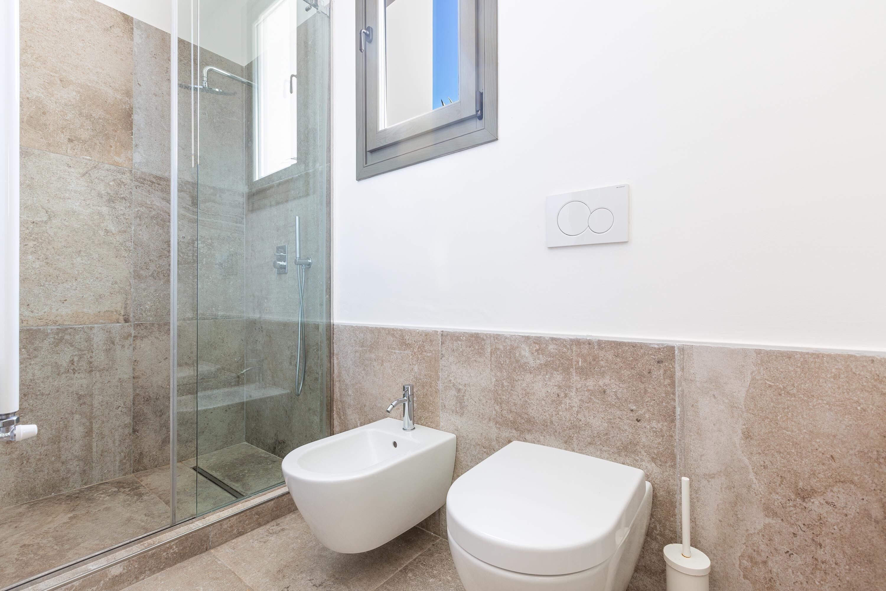 Un baño con ducha de vidrio, un bidé y un inodoro.
