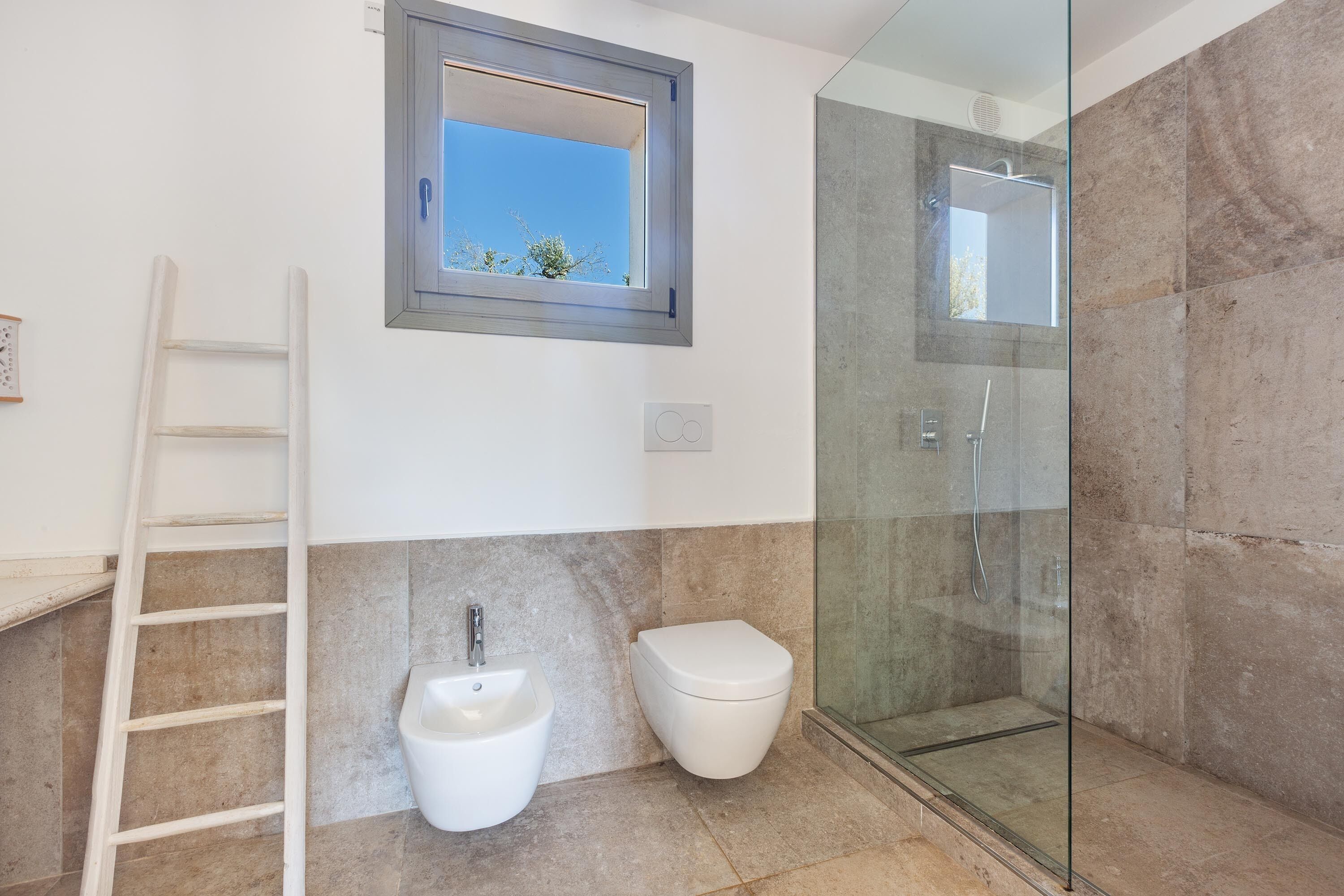 A modern bathroom with a glass-enclosed shower, a bidet, and a toilet.