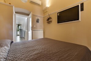 Un dormitorio con una cama grande, un televisor montado en la pared y una puerta que da a un baño.