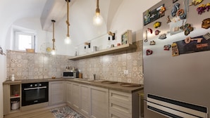 A modern kitchen with a built-in oven, microwave, and a refrigerator. There are hanging lights, a patterned backsplash, and a small window. - 3668 Appartamento Leonard by Barbarhouse (Carovigno)