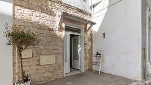 A narrow street with a stone building, a potted plant, and a white door. - 3668 Appartamento Leonard by Barbarhouse (Carovigno)