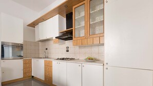 Moderni keittiö, jossa on valkoiset kaapit, ruostumattomasta teräksestä valmistettu uuni ja kaasuliesi.