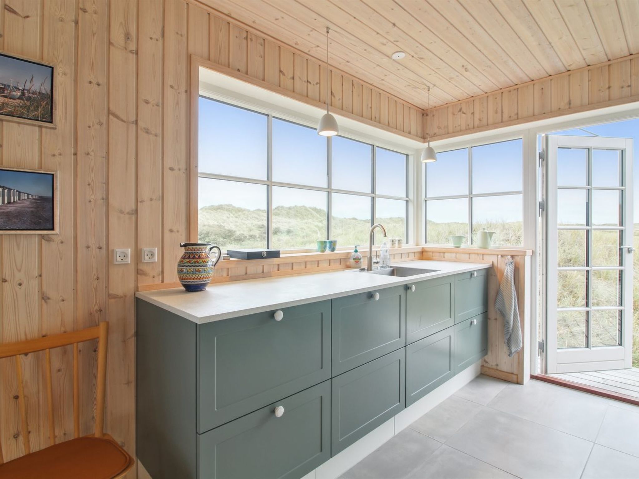 Une cuisine moderne dotée d’un grand îlot central, de murs en bois et de grandes fenêtres offrant une vue sur l’extérieur.