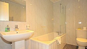A bathroom with a sink, bathtub, and toilet. - Tingle Creek Hotel (Kyle)