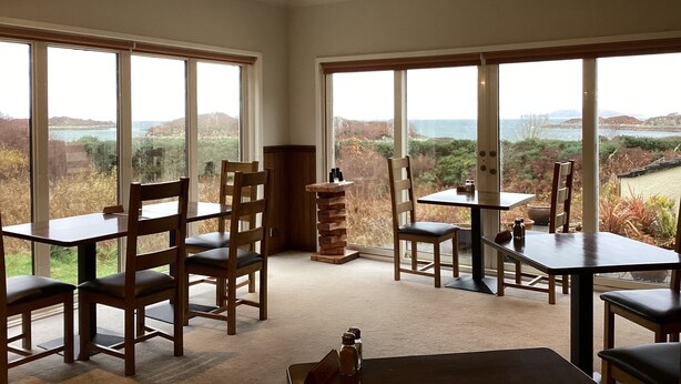 A dining area with large windows offering a scenic view of hills and water. - Tingle Creek Hotel (Kyle)