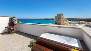 A rooftop terrace with a large bathtub, a stone structure, and a view of the sea. - 3358 Terrazza Belvedere by Barbarhouse (Melendugno)