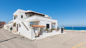 A white building with a red-tiled roof, a staircase leading to the entrance, and a view of the sea. - 3358 Terrazza Belvedere by Barbarhouse (Melendugno)