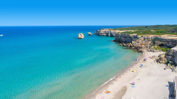 A coastal beach with clear turquoise waters, rocky cliffs, and a sandy shore with umbrellas. - 3358 Terrazza Belvedere by Barbarhouse (Melendugno)