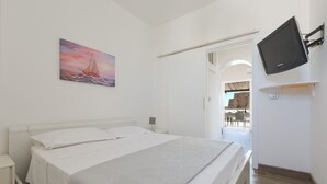 A bedroom with a bed, a painting, a mounted TV, and a view of a dining area. - 3358 Terrazza Belvedere by Barbarhouse (Melendugno)