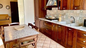 Une cuisine avec des meubles en bois, un plan de travail en granit et un coin repas comprenant une table et des chaises.
