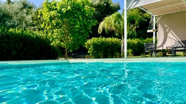 Une piscine aux eaux cristallines, entourée d’une végétation luxuriante, et un espace détente abrité.