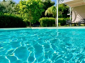 Une piscine aux eaux cristallines, entourée d’une végétation luxuriante, et un espace détente abrité.