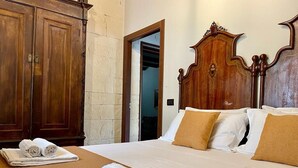 Une chambre d’hôtel avec un grand lit, une armoire en bois et une salle de bain visible à travers une porte ouverte.