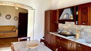 Une cuisine avec des meubles de rangement en bois, un pare-feu en carrelage et un coin repas comprenant une table et des chaises.