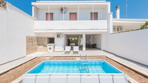 Un bâtiment à deux étages doté d’une piscine, d’un espace extérieur aménagé et d’un patio couvert.