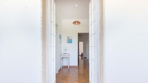 Un couloir aux murs blancs, doté d’un sol carrelé et d’un luminaire au plafond.