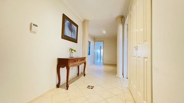 A hallway with a wooden console table, a framed picture, and a tiled floor. - 6 Bedroom House @ Gungahlin Town Center (Gungahlin)