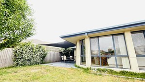 A modern house with a covered patio, a fenced backyard, and a view of the cityscape. - 6 Bedroom House @ Gungahlin Town Center (Gungahlin)