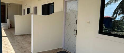 A hallway with white walls, a marble floor, and a door with a decorative pattern.