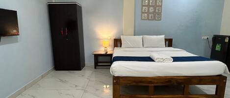 Habitación de hotel con cama, mesita de noche, lámpara, aire acondicionado, televisor y armario.