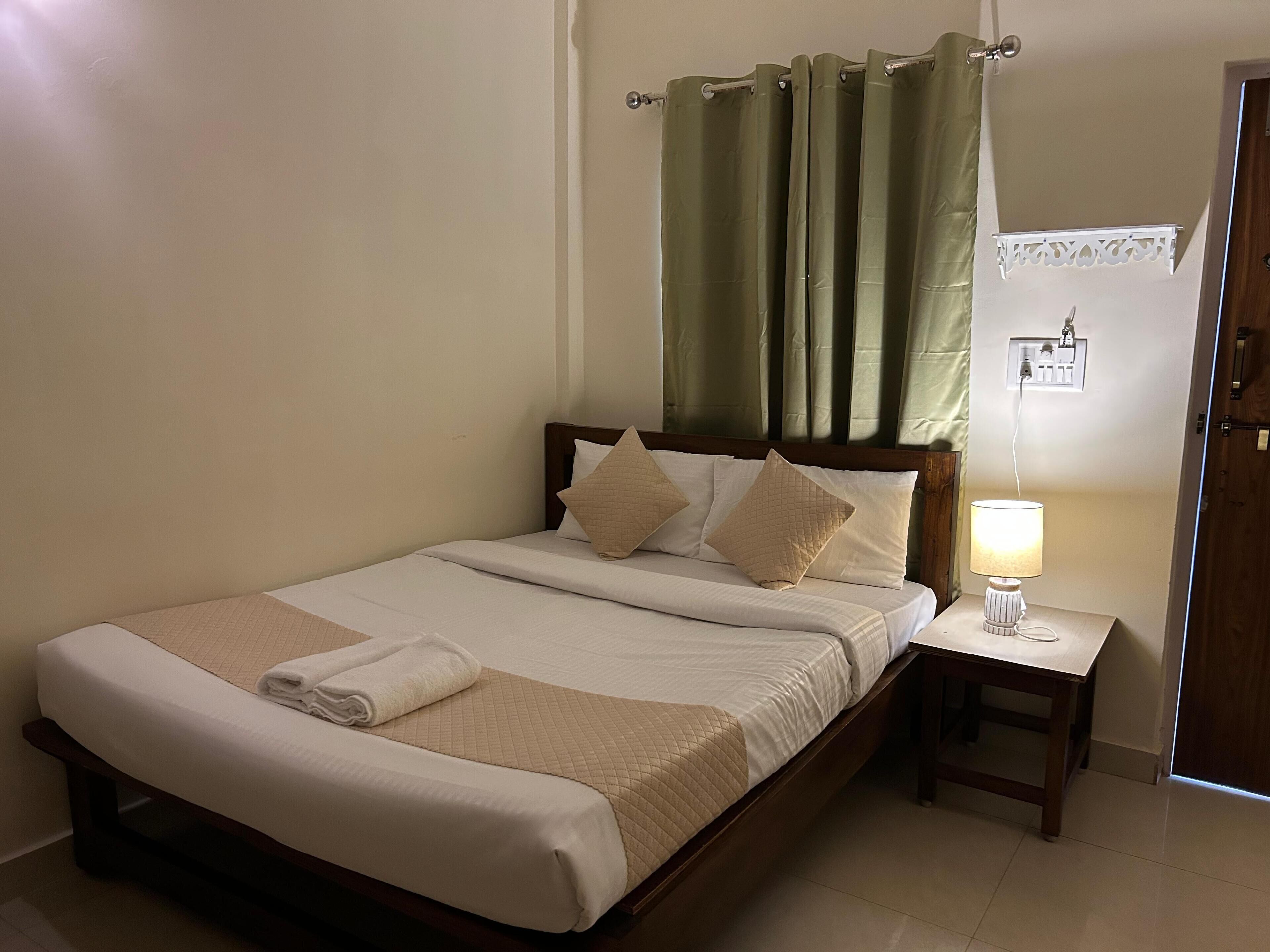 A neatly made bed with a quilted bedspread, a bedside lamp, and a wooden nightstand.