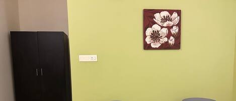 Una habitación con dos sillas grises, una mesa redonda pequeña, un armario negro y una obra de arte floral en la pared.