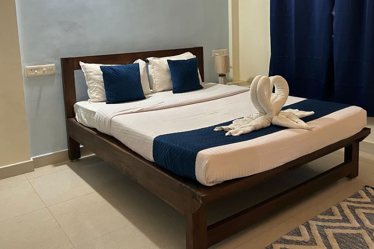A neatly made bed with a wooden frame, a blue and white bedspread, and decorative pillows.