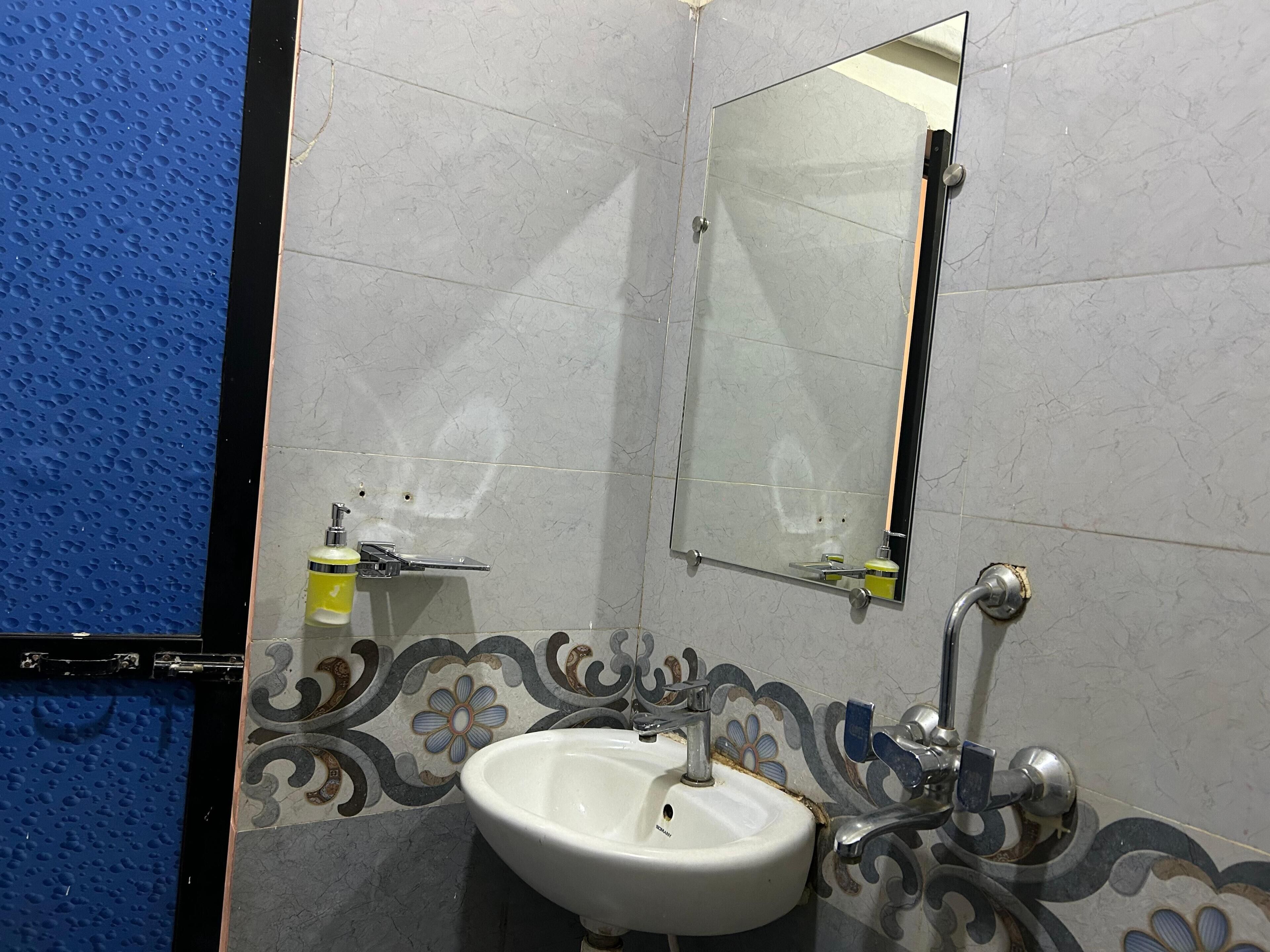 A bathroom with a white sink, a mirror, and a blue textured wall.