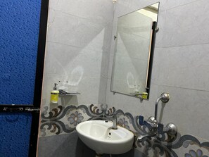 A bathroom with a white sink, a mirror, and a blue textured wall. - Aqua Wave by YogiTree Hotels (Morjim)